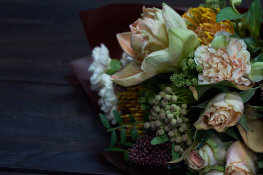 En närbild på en bukett med olika blommor och gröna blad.